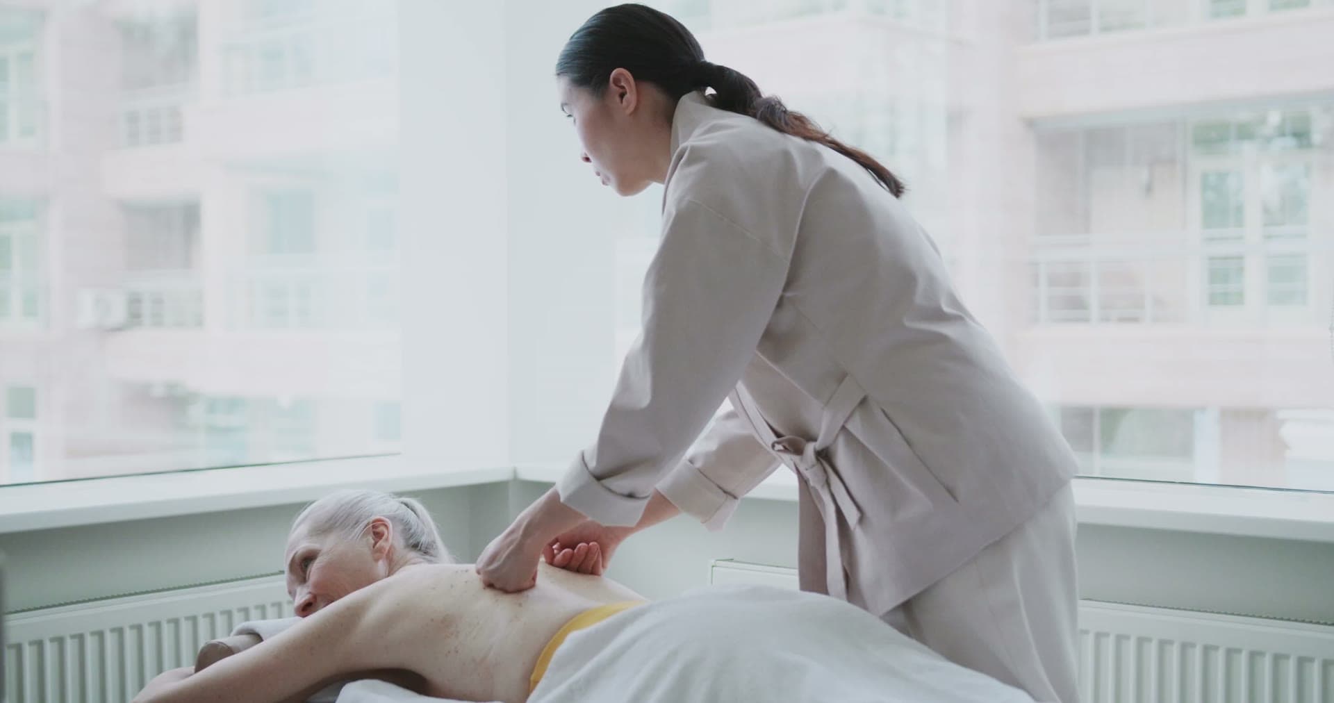 A therapist working on a reclining client in a calm, bright treatment room
